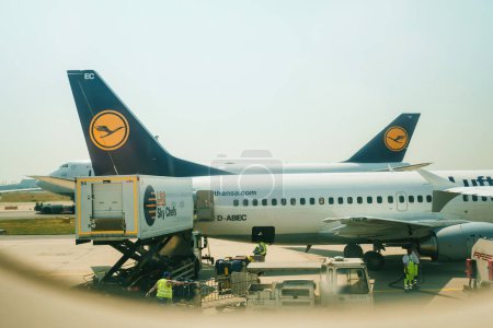 Foto de Alemania - Jul 6, 2015: Un avión, un Boeing 737 MSN 25149 perteneciente a Lufthansa después de aterrizar en un aeropuerto. Los trabajadores en equipo de protección están repostando el avión a reacción y cargándolo con - Imagen libre de derechos