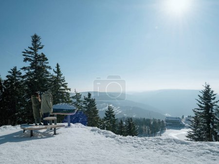 Photo for Two people admiring a tranquil winter landscape of Black Forest Schwarzwald, filled with snow-capped coniferous trees and mountain ranges, creating the perfect weekend holiday to enjoy natures beauty. - Royalty Free Image