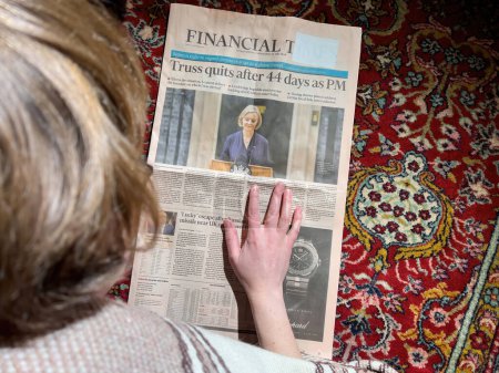 Foto de Londres, Reino Unido - 2 de febrero de 2022: Curiosa mujer leyendo en el piso de la alfombra de seda del salón el último Financial Times con el titular Liz Truss renuncia después de 44 días como Primer Ministro británico - Imagen libre de derechos