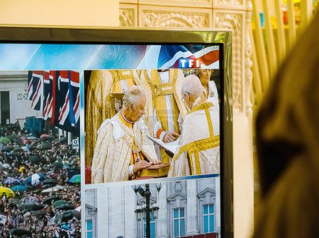 Foto de París, Francia - 6 de mayo de 2023: El rey Carlos III toma solemnemente el juramento de coronación con sus manos y dedos sobre la Santa Biblia, transmitido en vivo por el canal de noticias francés TF1. - Imagen libre de derechos