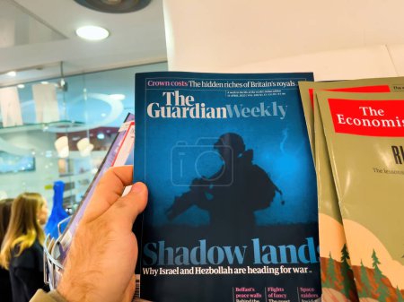 Photo for London, United Kingdom - 21 Apr 2023: A male hand holds a copy of the Guardian Weekly, featuring a story on the brink of war between Israel and Hezbollah - an important issue in journalism and mass - Royalty Free Image
