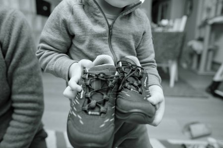 Foto de Frankfurt, Alemania - Mar 12, 2023: Un niño se destaca orgullosamente con un atuendo moderno y monocromo con elegantes botas lowa. Impermeable y aislado para el calor en condiciones frías de invierno. - Imagen libre de derechos