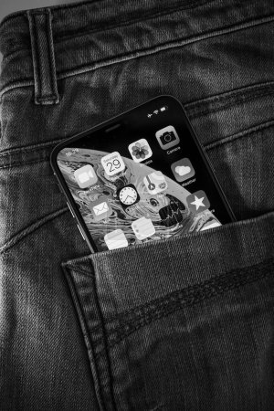 Foto de París, Francia - 29-sep-2018: Una llamativa foto en blanco y negro de un bolsillo de mezclilla con un smartphone Apple con su profunda pantalla OLED viva con múltiples aplicaciones. - Imagen libre de derechos