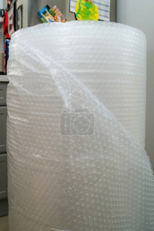 Foto de Un rollo grande de película de burbuja de aire en una cocina cerca de una nevera, que simboliza el transporte seguro y seguro de mercancías. - Imagen libre de derechos