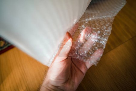 Foto de Un hombre está probando cuidadosamente un rollo gigante de película de envasado de burbujas de aire, demostrando la importancia del transporte seguro de mercancías. - Imagen libre de derechos