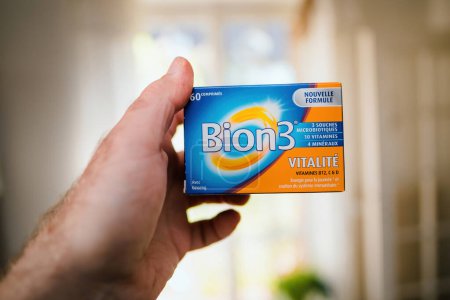Foto de París, Francia - 2 de mayo de 2023: Un primer plano de una mano masculina paciente sosteniendo un paquete de vitaminas que combaten la fatiga de Bion3 Vitality. - Imagen libre de derechos