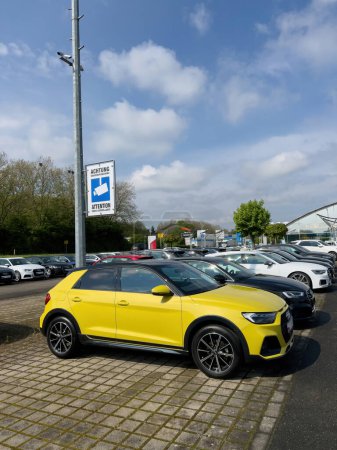 Foto de Alemania - 1 de mayo de 2023: Un elegante Audi SUV amarillo está estacionado fuera de un concesionario moderno y acogedor, esperando a su próximo afortunado propietario - Imagen libre de derechos