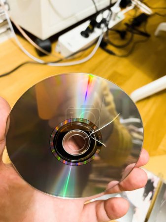 Photo for A man looks at a compact disk audio damaged during transport - Royalty Free Image