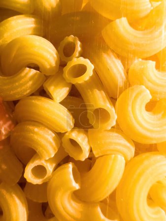 Foto de Un gran grupo de pastas amarillas sin cocer dispuestas, listas para ser cocinadas y disfrutadas por un grupo. Se evoca frescura, salubridad y bienestar bio producto orgánico - Imagen libre de derechos