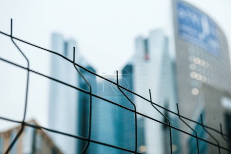 Photo for A tall, modern skyscraper stands amidst a bustling cityscape with construction and growth in progress. A protective fence adds to the security of this urban development. - Royalty Free Image