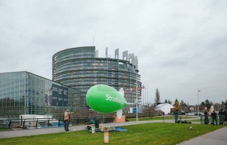 Foto de Estrasburgo, Francia - Nov 24, 2014: Un impresionante globo dirigible verde con Estrasburgo inscrito en él está siendo preparado por personas frente al edificio del parlamento, un símbolo de ecológico - Imagen libre de derechos