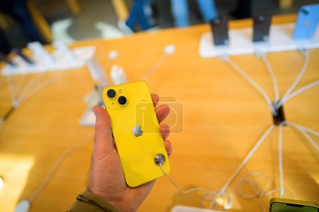 Foto de París, Francia - 20 de marzo de 2023: Un primer plano de una mano sosteniendo un iPhone 14, con la parte posterior de su moderno dispositivo con vidrio amarillo - tecnología móvil que permite la comunicación a través de la tecnología inalámbrica - Imagen libre de derechos
