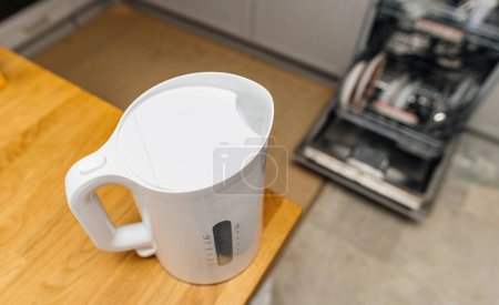 Téléchargez les photos : Une cuisine moderne avec une bouilloire en acier inoxydable bouillante sur le comptoir, entouré d'un lave-vaisselle ouvert - en image libre de droit