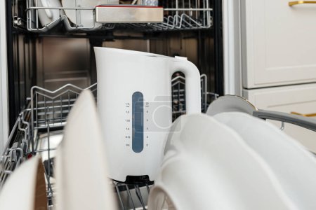 Foto de Un primer plano de un moderno lavavajillas blanco con un hervidor de agua en el interior, que muestra el diseño económico y la tecnología utilizada para limpiar los platos en los hogares. - Imagen libre de derechos