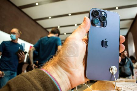 Photo for Paris, France - Sep 22, 2022: A close up of a hand confidently holding the new iPhone Pro 14 Max in an Apple Store, with customers in the background. - Royalty Free Image