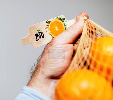 Photo for A young person holds a net of organic mandarines, enjoying the health benefits and sweet taste of their healthy eating choices. - Royalty Free Image