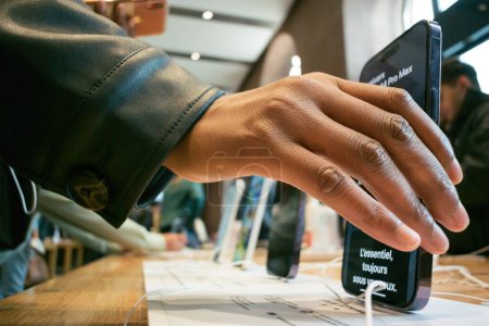 Téléchargez les photos : Paris, France - 22 sept. 2022 : Une femme d'origine noire met son nouvel iPhone Pro 15 en charge dans l'Apple Store dès son premier jour de vente, illustrant un environnement de travail chargé. - en image libre de droit