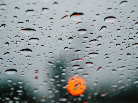 Photo for Raindrops drench the car window as red light bokehs shine. The monsoon seasons motoring beauty captured in wet, full-frame close-up mode of transportation. No people. - Royalty Free Image
