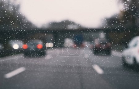 Foto de Una ventana transparente del coche revela un paisaje urbano lluvioso, nevado y húmedo. La visión borrosa del tráfico refleja las condiciones climáticas heladas y heladas fuera. - Imagen libre de derechos