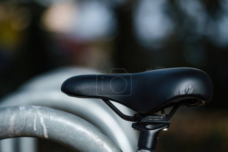 Photo for A sleek black bicycle wheel with leather bike seat and gear details in sharp focus. The defocused background adds depth to this transportation macro shot. - Royalty Free Image