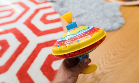Foto de Una mano sosteniendo un juguete giratorio multicolor como regalo para los niños, con una persona en el marco mostrando los niños vibrantes y divertidos presentes. - Imagen libre de derechos