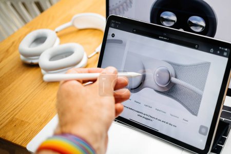 Photo for Paris, France - Jun 6, 2023: User with pencil pointing to external battery that supports up to 2 hours of use, for Apple Vision Pro mixed reality XR headset. Priced 3,499 USD - future of computing - Royalty Free Image