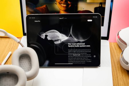 Foto de París, Francia - 6 de junio de 2023: Lente de desplazamiento inclinable sobre descripción de audio espacial en la mesa de la sala creativa con la página web de Apple en el iPad Pro que muestra los auriculares XR de realidad mixta Apple Visión Pro. Precio 3.499 - Imagen libre de derechos