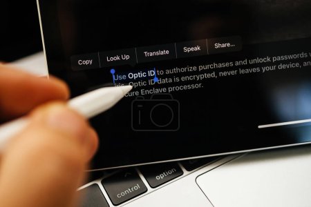 Foto de París, Francia - 6 de junio de 2023: Selección manual con lápiz del texto Use OpticID en la página web de Apple en el iPad Pro, que muestra los auriculares XR de realidad mixta Apple Visión Pro. Precio 3,499 USD - futuro de - Imagen libre de derechos