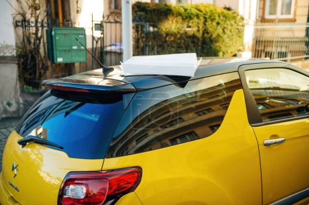 Foto de París, Francia - 25 de diciembre de 2015: Caja de pizza blanca en la azotea de un Citroen DS amarillo estacionado en un paisaje urbano, rodeado de arquitectura urbana y otros vehículos. Un coche francés y un taxi amarillo - Imagen libre de derechos