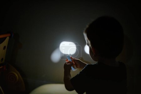 Foto de Un niño sostiene un prisma de cristal que explora su forma y reflejo en la fascinación. Brillante y texturizado, proyecta una sombra en su cara y pared - foto de desplazamiento basculante - Imagen libre de derechos