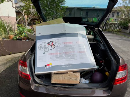 Foto de Alemania - Feb 4, 2023: Un vehículo que acelera transporta cajas de cartón en su maletero abierto, mostrando un modo eficiente de transporte para este material reciclable. - Imagen libre de derechos