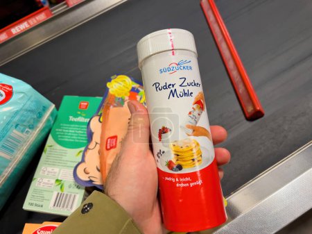 Téléchargez les photos : Allemagne, 4 mars 2023 : Une main tient la poudre de sucre à la caisse du supermarché Rewe. Perspective personnelle dans une marque Sudzucker allemande - en image libre de droit