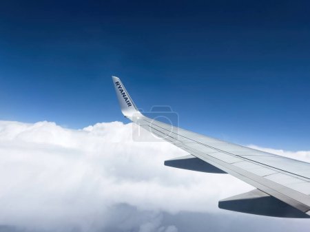 Photo for Jun 22, 2023: Aircraft wing slicing through blue sky, as airliner takes flight. Ryanair Airlines offers first-class travel experience. Euphoric journey through the clouds. - Royalty Free Image