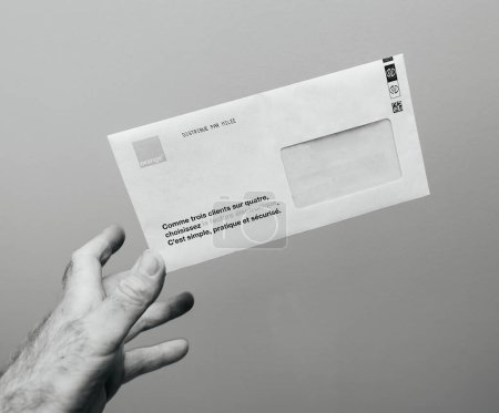 Photo for Paris, France - May 30, 2023: An addressed envelope with an invoice inside, reaching addressees hand - monthly paper telecommunication invoice from Orange Telecom provider - Royalty Free Image