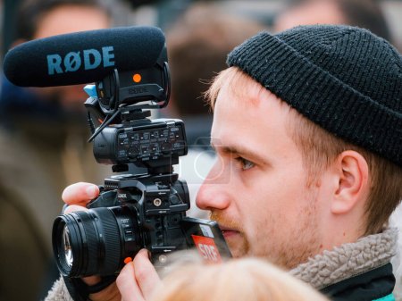 Téléchargez les photos : Strasbourg, France - 29 mars 2023 : Un journaliste de la station SRF capte l'énergie d'une manifestation à Strasbourg avec sa caméra Panasonic GH5. - en image libre de droit