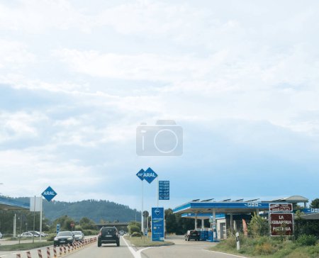 Photo for Schiltach, Germany - Jul 14, 2022: Aral as station stands out against the clear sky. A road sign points the way on the highway, as gas prices change. - Royalty Free Image
