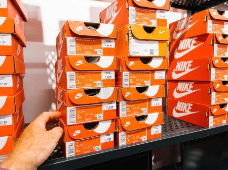 Téléchargez les photos : Roppenheim, France - Juillet 11, 2023 : Homme prise de main à partir de étagère Nike running boîtes à chaussures de sport en magasin - en image libre de droit