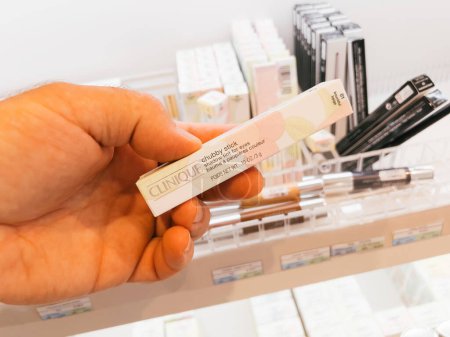 Téléchargez les photos : Roppenheim, France - 11 juillet 2023 : Dans un magasin de cosmétiques, une main masculine sélectionne une teinte d'ombre Clinique pour les yeux des étagères. - en image libre de droit