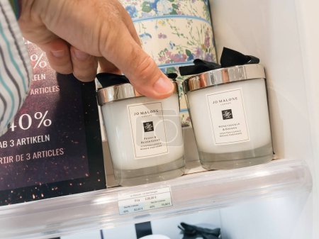 Foto de Roppenheim, Francia - 11 de julio de 2023: En una tienda, una mano de hombre selecciona una vela perfumada. Decisión de fragancia en curso - Jo Malone marca. - Imagen libre de derechos