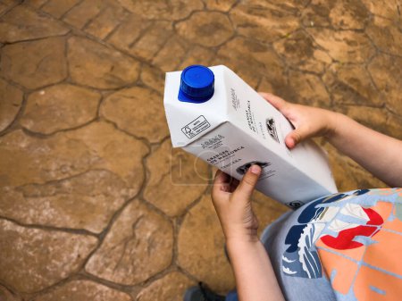 Foto de Mallorca, España - Jun 30, 2023: Un niño tiene un paquete de leche de Granjas de Mallorca, disfrutando de una bebida refrescante. - Imagen libre de derechos