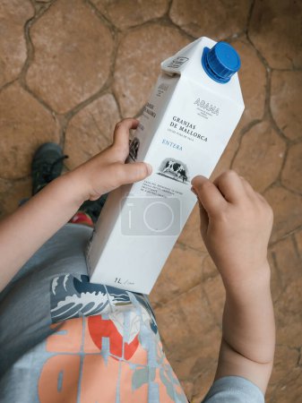 Foto de Mallorca, España - Jun 30, 2023: bebé sostiene paquete de leche Granjas de Mallorca. Vista aérea captura la inocencia y la curiosidad de los niños pequeños. Perfecto para mostrar la alegría de la infancia. - Imagen libre de derechos