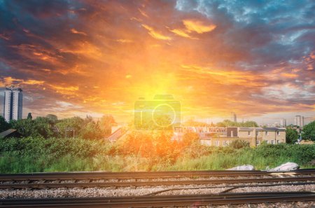 Photo for Sun explosions effect over London suburbs from the in motion train - houses, fields, skyscrapers - Royalty Free Image