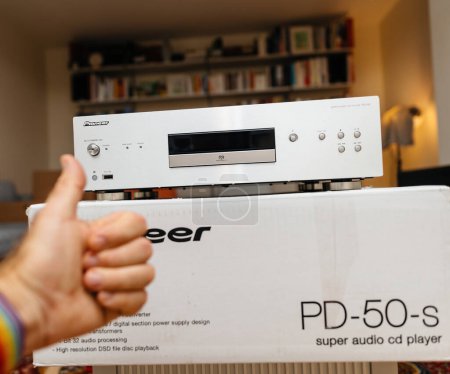 Foto de Hamburgo, Alemania - 24-jul-2023: Happy owner thumb up in living room featuring cardboard box with new Pioneer PD-50-2 super audio cd SACD player for hifi musicality and audition - Imagen libre de derechos