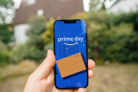 Photo for Hamburg, Germany - Jun 12, 2023: POV male hand holding new iphone 15 pro in hand with Amazon prime day shopping website promo on the liquid retina display - garden background - Royalty Free Image