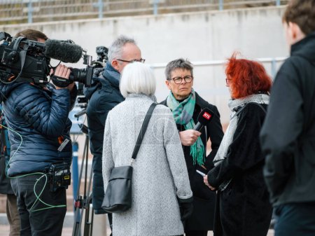 Photo for Strasbourg, France - Mar 29, 2023: A RTS reporter interviewing a Swiss senior woman peacefully protest in front of the European Court for Human Rights, holding placards as they demand action on - Royalty Free Image