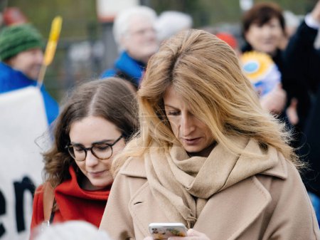 Foto de Estrasburgo, Francia - 29 de marzo de 2023: Mujer adulta rodando en su teléfono leyendo mensajes de texto durante una protesta pacífica frente a la Corte Europea de Derechos Humanos, sosteniendo pancartas mientras exigen acción - Imagen libre de derechos
