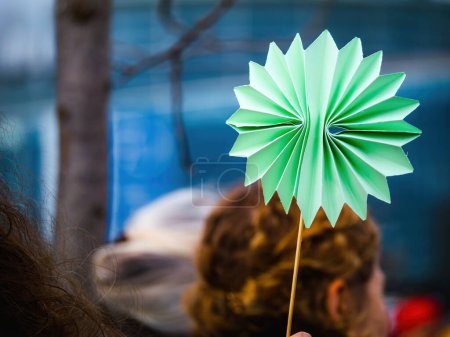 Foto de Defensor del medio ambiente sostiene flor de papel en protesta, visto desde atrás, un poderoso mensaje para la sostenibilidad - Imagen libre de derechos
