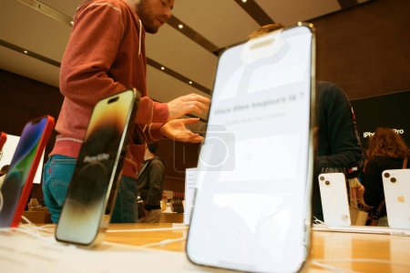 Foto de París, Francia - 22 de septiembre de 2023: Los clientes esperan dentro de una Apple Store durante el lanzamiento del nuevo iPhone Pro. Fondo muestra compradores emocionados y los últimos gadgets. - Imagen libre de derechos