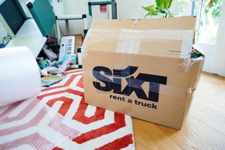 Photo for Bremen, Germany - Aug 14, 2023: Empty living room - sixt Rent a Truck cardboard boxes in a well-lit living room, signaling a move to a new home - Royalty Free Image
