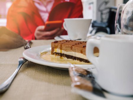 Téléchargez les photos : Vue rapprochée d'un gâteau au chocolat, d'un café et d'une femme en rouge à une table de petit-déjeuner intérieure. - en image libre de droit